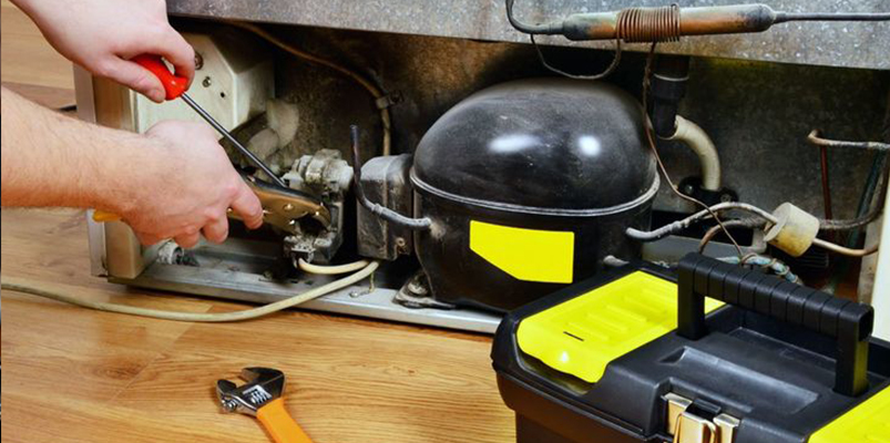 Technician repairing fridge compressor unit — KTech Appliance Services Perth