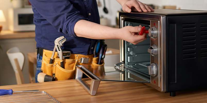 Technician repairing small benchtop countertop oven — KTech Appliance Services Perth